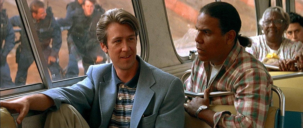 Alan Ruck and Carlos Carrasco sit next to each other on a bus with a bomb onboard. Speed.