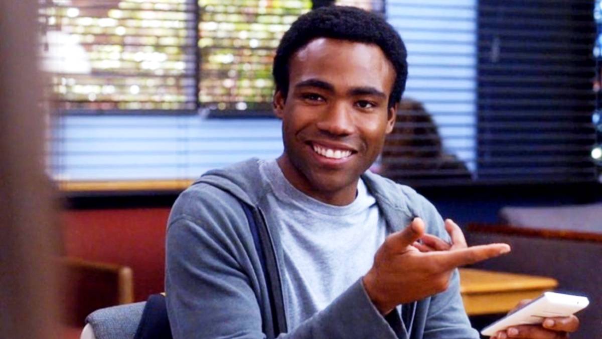 From Community: Donald Glover as Troy Barnes smiles and points camera right.