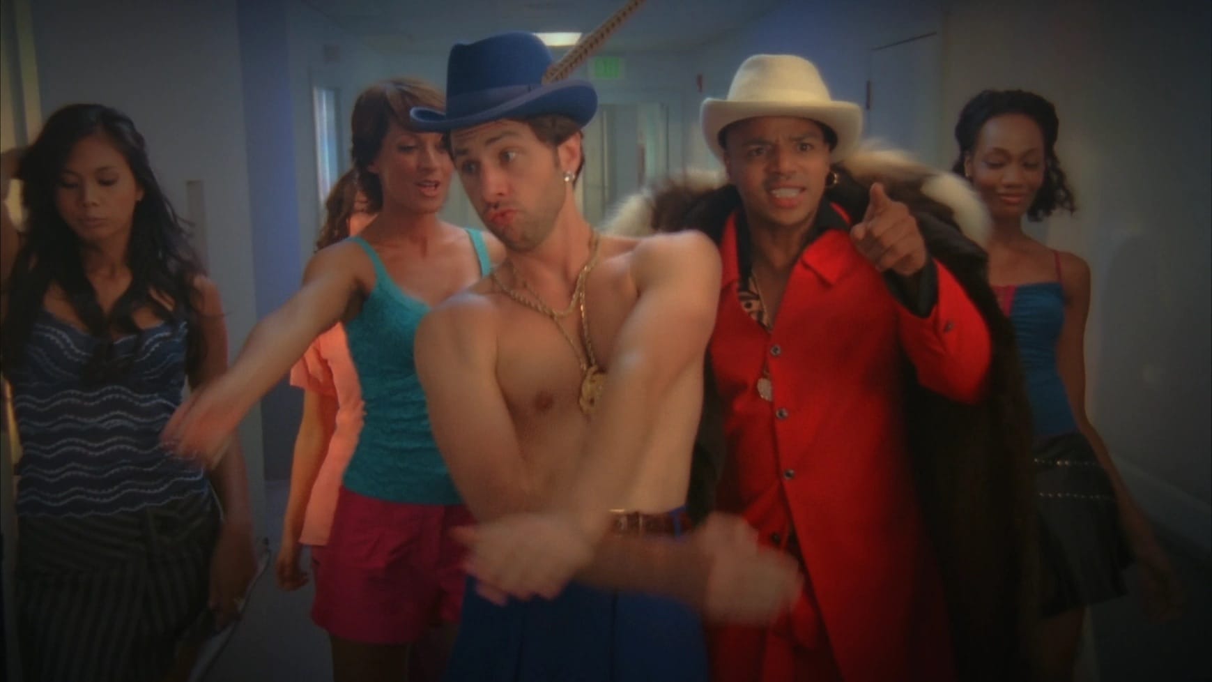 Scrubs: J.D. and Turk walk down the hallway wearing Fedoras and surrounded by women. J.D.'s shirt is absent.