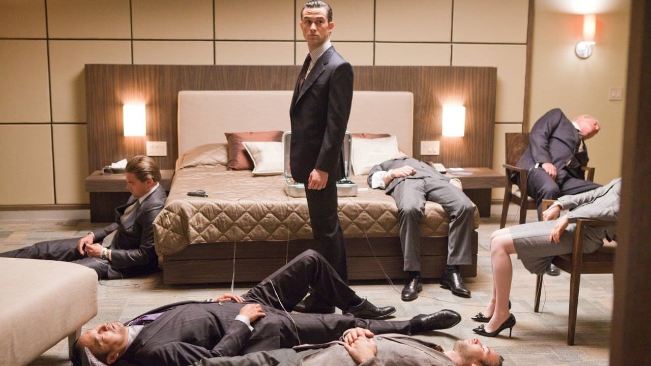 Inception: Arthur stands in the middle of a hotel room, surrounded by people lying down hooked up to the dream infiltration machine.