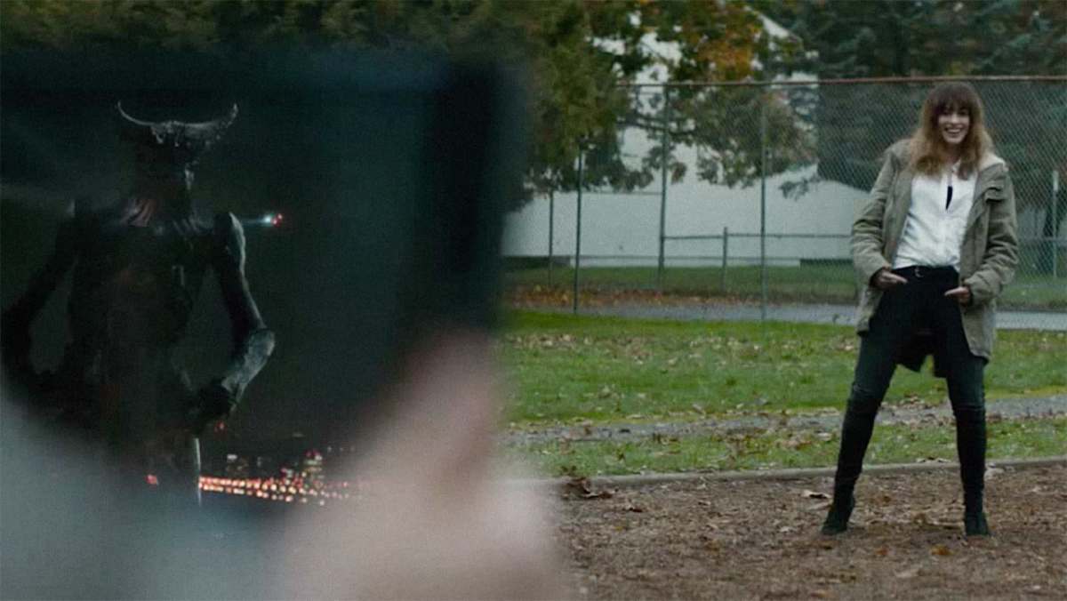 Colossal: Anne Hathaway does a little dance in a playground next to a live video feed of a kaiju in Seoul doing the same exact dance.