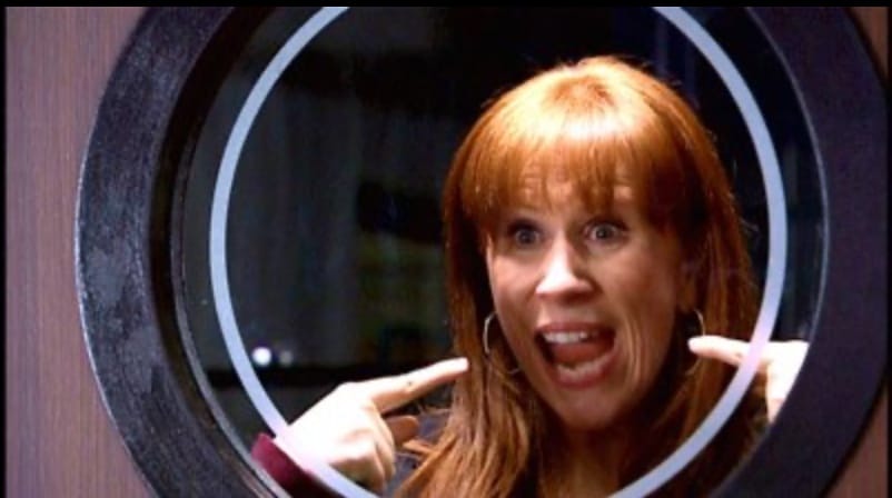 Doctor Who: Donna Noble looks through a circular window, smiling and pointing to herself with both hands.