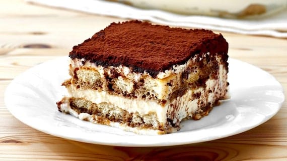 A delicious looking slice of tiramisu on a white plate.