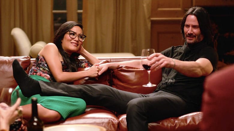 Still from Always Be My Maybe with Ali Wong and Keanu Reeves reclined together on a couch with wine glasses.