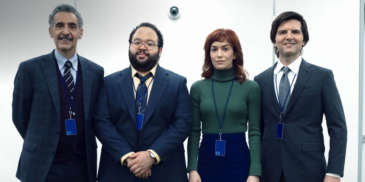 The Innies of Severance taking a group photo in the office with a security camera behind them.