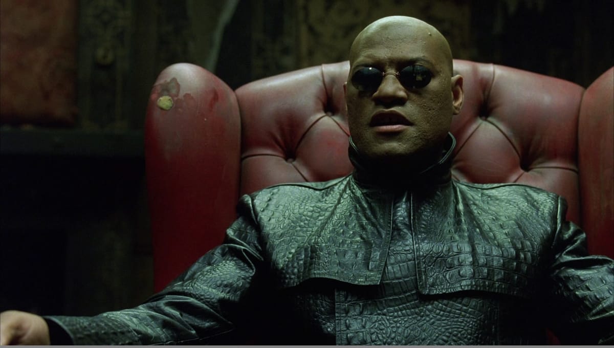 The Matrix: Morpheus sits in a red leather chair, talking about The Matrix and looking super cool.