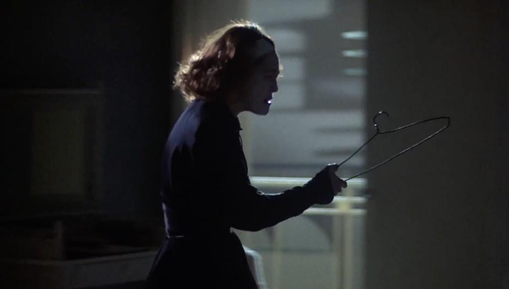 Mommie Dearest: Faye Dunaway grabs a wire hanger out of a closet in a dark room. She really doesn't like wire hangers.