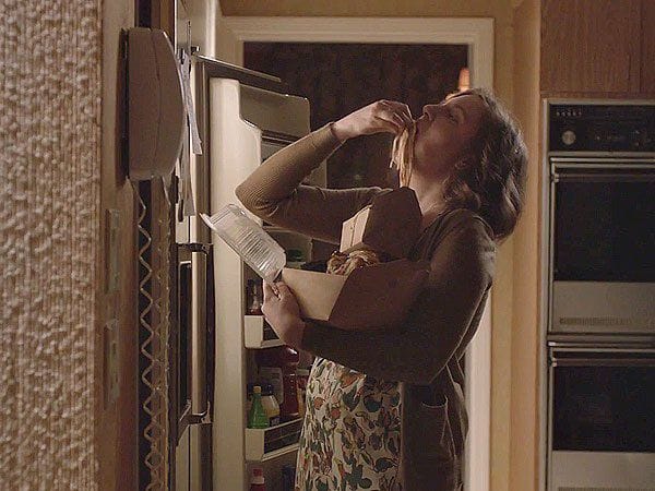 From Girls: Hannah stands in front of a fridge and shoves a handful of leftovers from a carry-out box directly into her mouth.