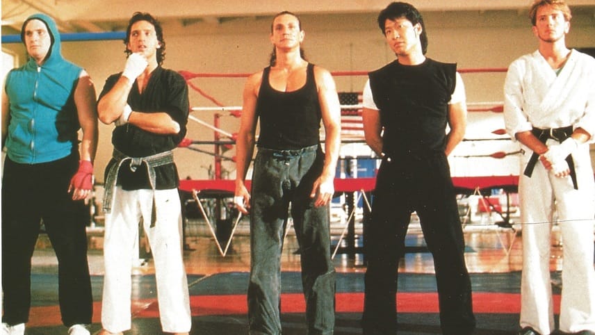 Screenshot from 1989's Best of the Best with an unlikely team of five martial arts guys standing in a row inside a gym.