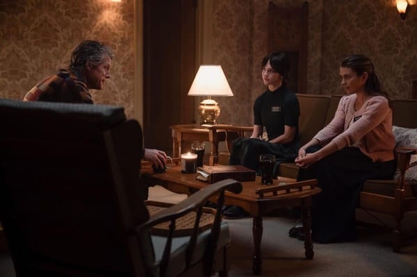 The film Heretic. A dimly lit living room. Mr. Reed sits opposite from Sisters Barnes and Paxton.