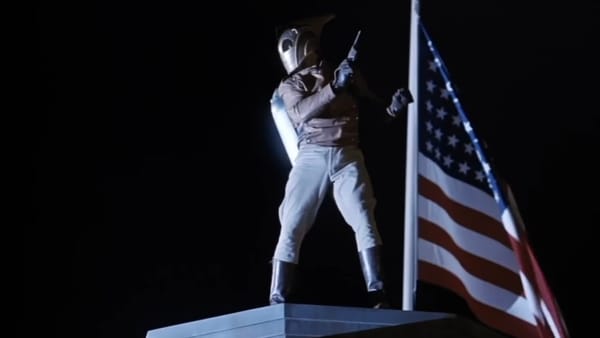 From The Rocketeer. The iconic night time shot of Cliff in full Rocketeer getup, posing next to an American Flag before going to punch some Nazis.
