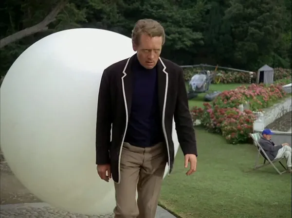 From The Prisoner: Number 6 walks through a courtyard followed by an inflated, white, ball thing.